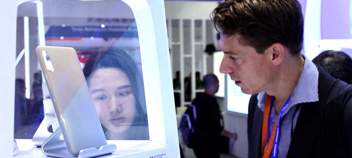 Los visitantes observan los teléfonos móviles 5G recubiertos con la tecnología avanzada de PPG en el stand C-Touch Display y Exhibit Shenzhen 2019 de la compañía